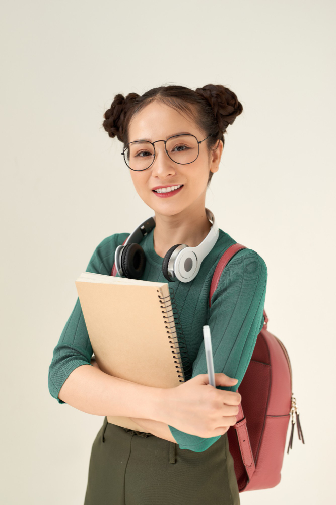 asian-student-woman-wearing-backpack-holding-notebook-isolated-white-background-with-happy-face-standing-smiling-with-confident-smile-showing-teeth